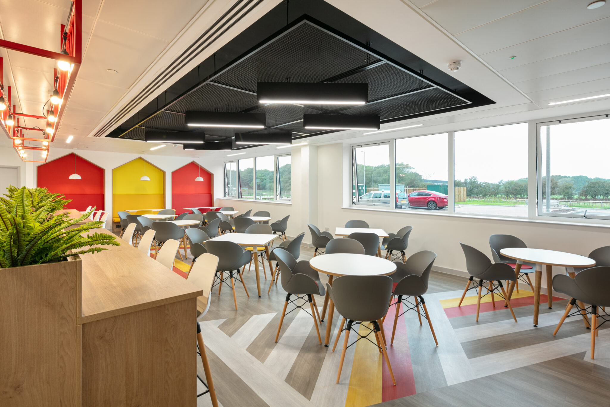 open-plan kitchen and breakout area designed for social interaction, equipped with comfortable seating, feature lighting, and bold décor