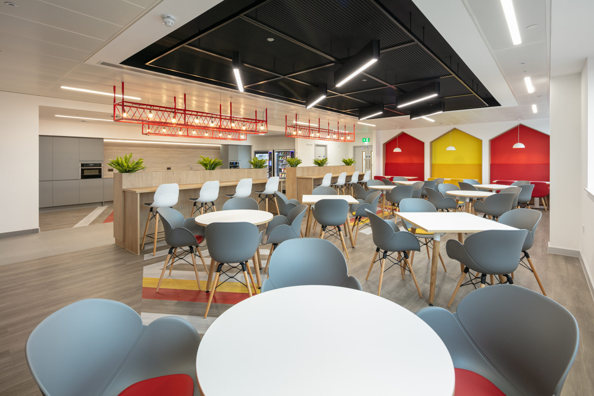 open-plan kitchen and breakout area designed for social interaction, equipped with comfortable seating, feature lighting, and bold décor